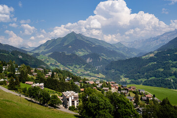 Fototapeta na wymiar High agle panorama of alpine village Leysin with Pic Chaussy mountain in the background in summer under a blue sky with some white clouds