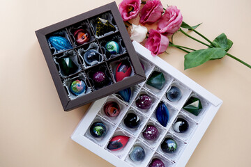 A set of handmade candies in festive packaging. Space design. Candy on a light background and decor of rose flowers. Black and white box