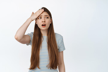 Worried girl forgot smth. Young woman hold hand on forehead, look aside upset, remember something, has trouble, stands against white background