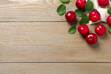 Naklejka na ściany i meble Fresh ripe cherry plums on wooden table, flat lay. Space for text