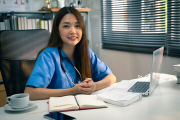 Portrait shot of female doctor while working on laptop in doctor’s office.