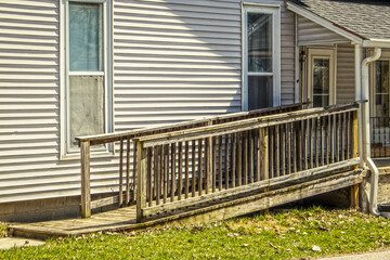 Rustic wooden handicap ramp on vintage house with fabric tacked up inside windows and metal...