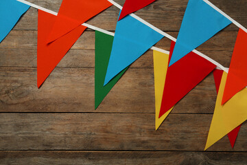 Buntings with colorful triangular flags on wooden background, space for text