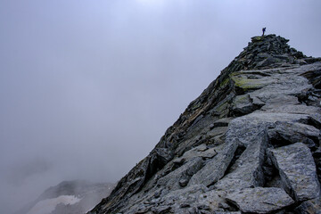 Alpinista sulla vetta di una montagna avvolta nella nebbia