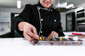 hand of latin woman pastry chef wearing black uniform in process of preparing delicious sweets...