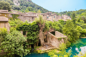 Fototapeta na wymiar A glimpse of the small village of Stifone, on the Nera river. Umbria, Terni, Italy. The walls of stones and bricks. The bridge over the river with clear blue waters.