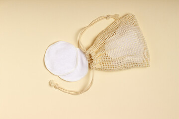 Cotton reusable makeup remover pads in a cloth bag on a beige background. The concept of ecology and conscious consumption. Reusable cotton pads
