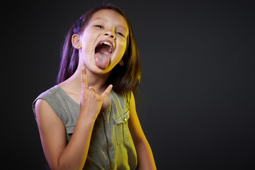 child girl with crazy expression doing rock symbol