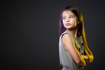 unsatisfied little child girl on dark background.
