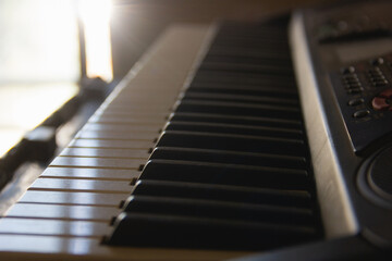 Close up on black and white piano music keyboard keys with sunlight entering through window. Home composer, teaching lessons, art creation, inspiration concepts