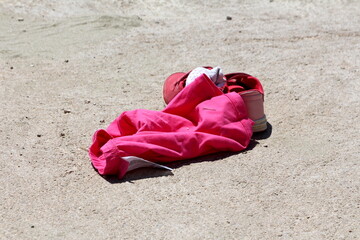 Pink woman boxer shorts next to pink and white women running shoes filled with used socks left at local beach while girl went swimming on warm sunny spring day