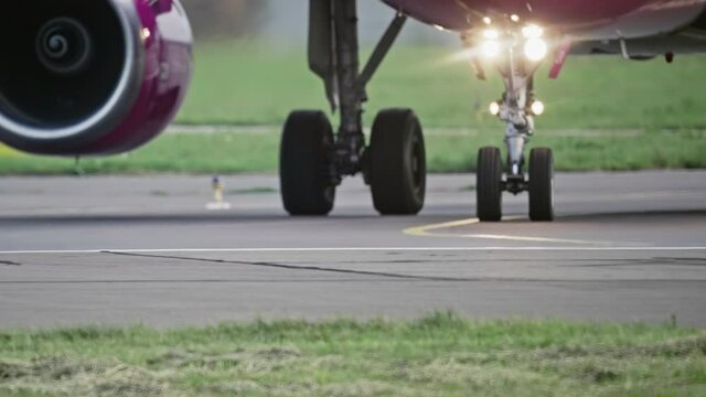 Close-up of the wheels of an airplane traveling on the runway. The plane with a turbine and headlights goes to take off.