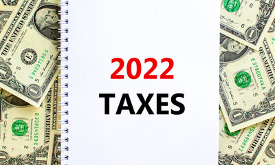 2022 taxes new year symbol. Words '2022 taxes', on white note. Beautiful background from dollar bills. Business and 2022 taxes new year concept. Copy space.