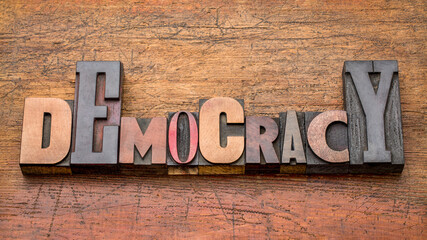 democracy word abstract in mixed vintage letterpress wood type against rustic wooden background, political concept