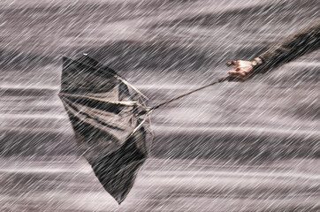 man holding umbrella in wind and rain