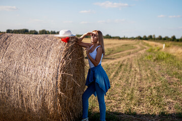 Woman standing  near a straw bale