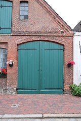 Grünes Scheunentor oder Garagentor aus Holz als Garage in einem alten Backsteinhaus in Friedrichstadt, Schleswig-Holstein, Deutschland
