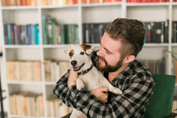 Happy male owner of jack russell terrier dog, feels responsibility of caring about pet, standing...