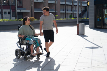 Young disabled woman in wheelchair dating with her boyfriend outdoors