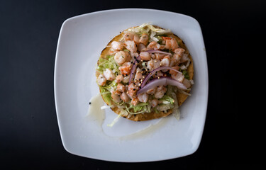 photo from above of a Mexican tortilla with shrimp and vegetables on a white plate and black background - typical Mexican food