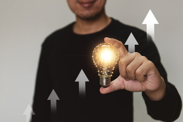 Hand holding a light bulb rises up with investment arrow for business growth and profit increase concept.