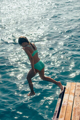 summer fun - kid jumping to the water from wooden piere