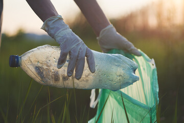 Volunteer young woman collecting trash outside, picking up waste, land pollution and save earth...