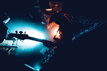 Silhouette Of Guitar Player In Action On Stage. Band Silhouette. View of stage during rock concert with musical instruments and scene stage lights, rock show performance. Guitarist plays solo on stage