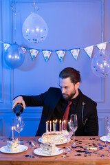 attractive young man celebrates his birthday alone by pouring himself champagne and enjoying his solitude