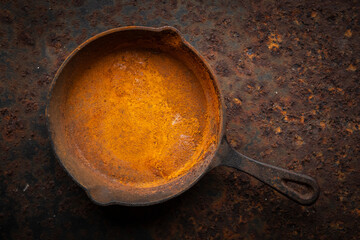 rusty cast iron skillet on a dirty rust metal plate texture background, top view