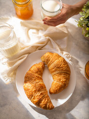 On a white background - two croissants, milk, jam. Classic French breakfast. Low angle view....