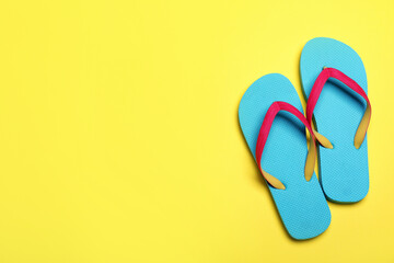 Stylish flip flops on yellow background, flat lay. Space for text