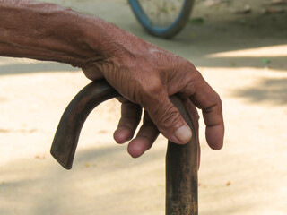 Indian Elderly Man kept his hand on walking cane on the street in the village of Bangladesh