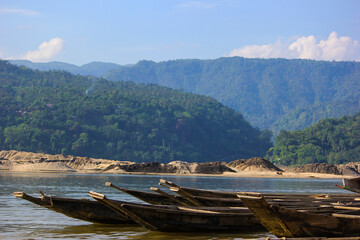 Fototapeta na wymiar Lots of Wooden Row boats anchored at mountainous river shore in Sylhet, Bangladesh. 