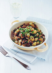 Gnocchi with onion and mushrooms. Bright wooden background. Copy space.	