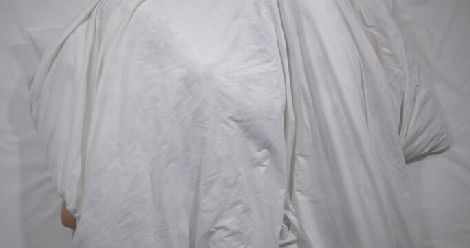  Top view of caucasian couple having sex to bed   in light room. High angle shooting.  Man amd woman making love under a blanket. They look at each other, smile and hide under a blanket 4k 