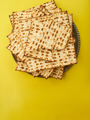 Traditional Jewish bread matzah on a sunny yellow background. High angle view. There is an empty space for an inscription. Celebrating Jewish Passover, traditional kosher bread.