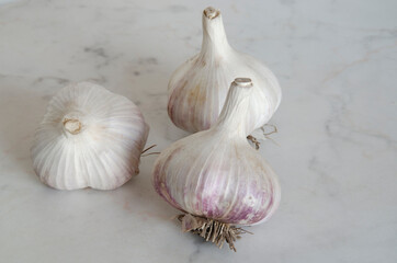 Three heads of garlic close-up on a white dining table. Healthy food, seasoning, a delicious addition to food.