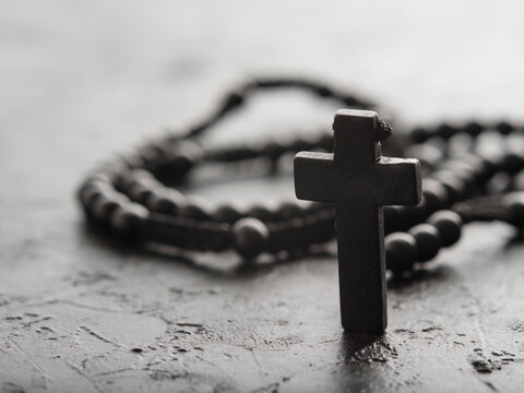 Rosary and crucifix on a gray background. Minimalism. Close-up. The concept is religion, Christianity, Catholicism, faith, spirituality, prayer, meditation.