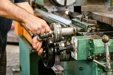 The worker sets the size of the feed on the dial on the lathe. - obrazy, fototapety, plakaty
