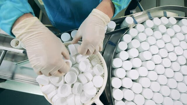 Tubs with pills are getting closed by a pharma worker