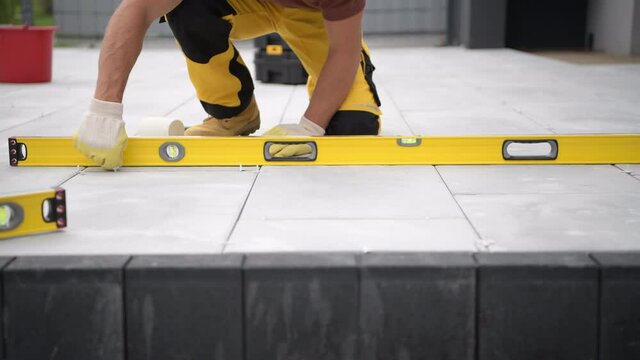 Concrete Brick Paving by Caucasian Construction Industry Worker. Spirit Level Tool Using.