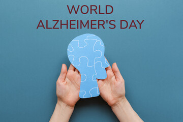 World Alzheimer's day. Female's hands holding a paper human head with puzzle ornament....