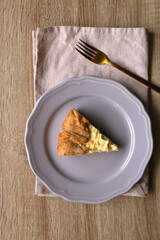 Slice of cheese and leek quiche on wooden table. Flat lay.