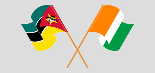 Crossed and waving flags of Mozambique and Republic of Ivory Coast