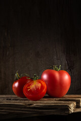 moody portrait of ripe fresh tomatoes with tails on old boards on a wooden background. beautiful artistic still life in a rustic style with copy space