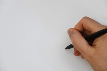 A male hand and black ink pen are shown up close, just before writing on a plain white surface.