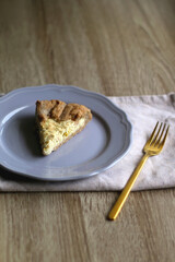 Slice of cheese and leek quiche on wooden table. Selective focus.