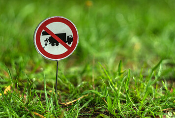 A round red sign prohibiting the dumping of garbage waste. It is installed on the green grass. Space for the text.