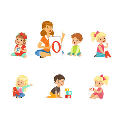 Cute Children Learning Alphabet and Playing in Nursery School with Teacher Sitting on the Floor with Card and Cube Vector Set
